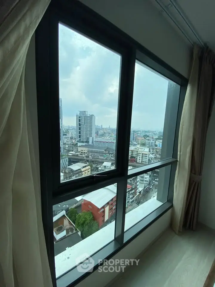 Stunning cityscape view from high-rise apartment window with modern curtains.