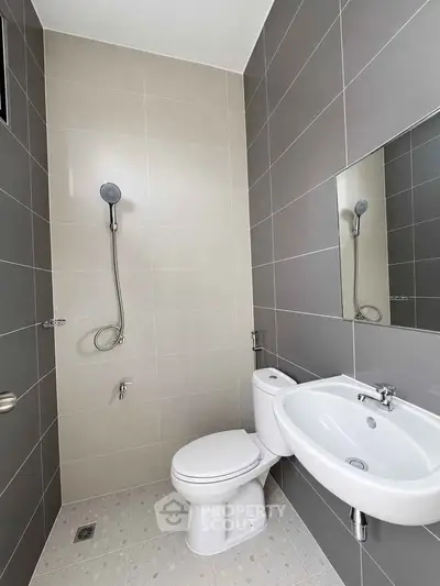 Modern bathroom with sleek design featuring a shower, toilet, and sink in neutral tones.