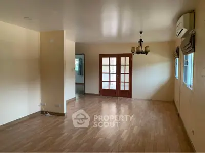Spacious living room with wooden flooring and elegant chandelier in a cozy home.