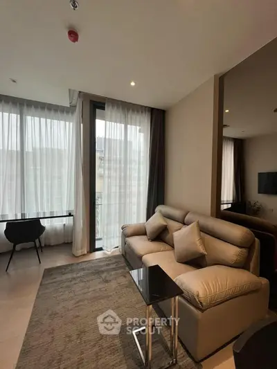 Modern living room with large windows and stylish furniture in a high-rise apartment.