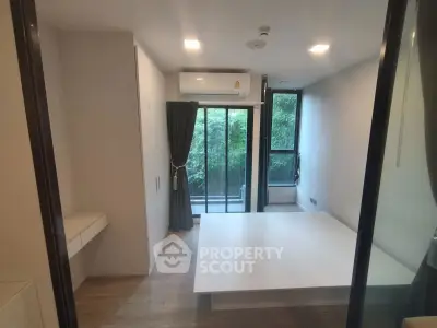 Modern bedroom with large window and balcony access, featuring sleek design and natural light.