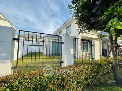 Modern two-story house with lush garden and secure fencing