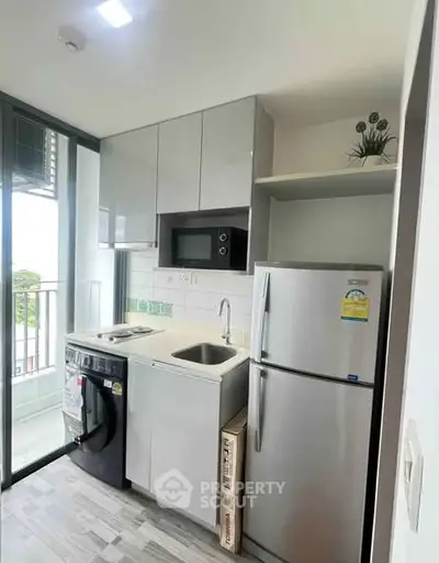 Modern compact kitchen with balcony access, featuring sleek appliances and stylish cabinetry.