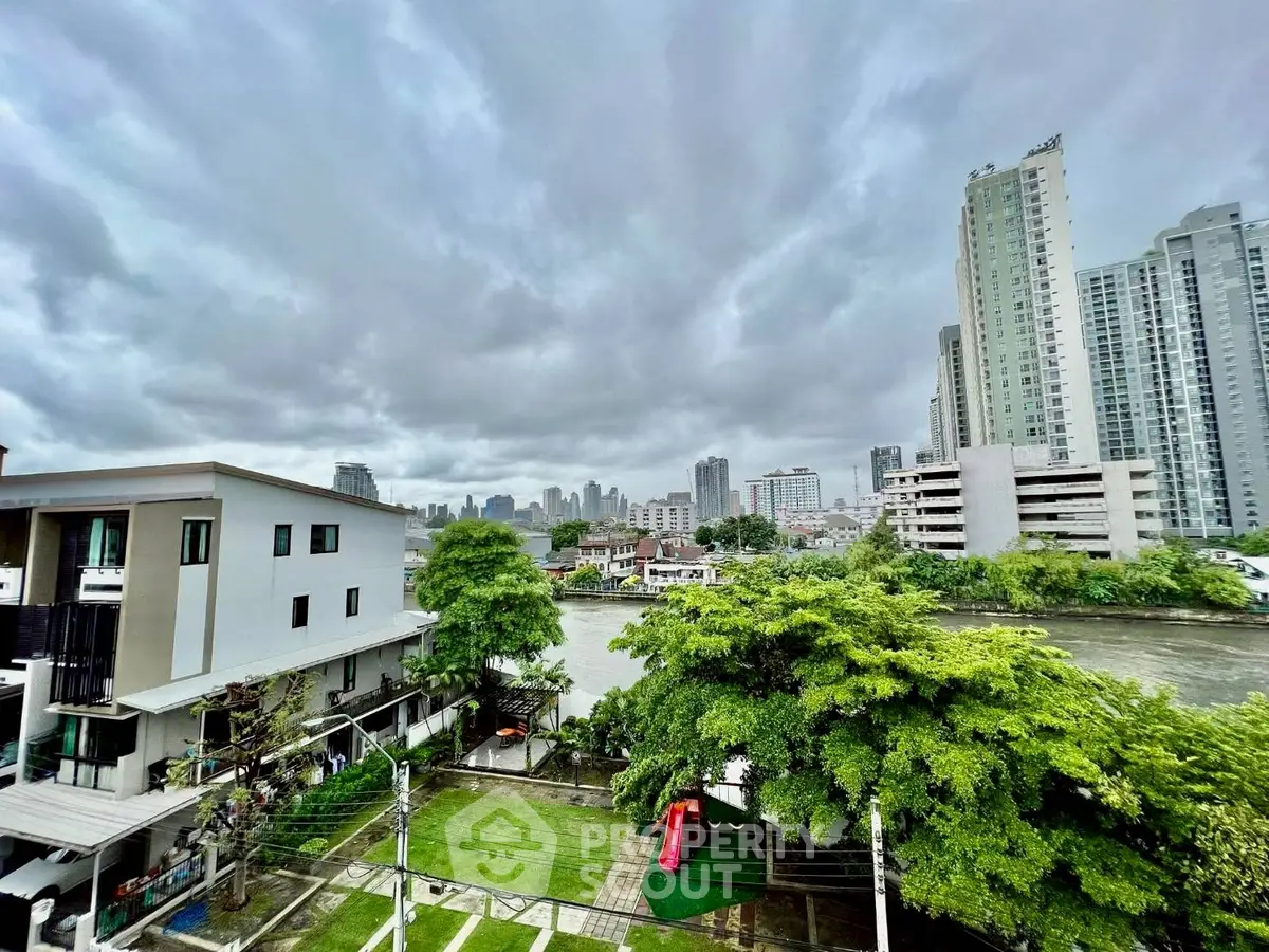 Stunning cityscape view from a high-rise balcony overlooking lush greenery and river, perfect urban living.
