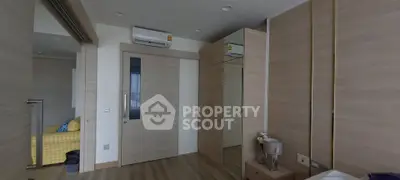 Modern bedroom with sliding door and mirrored wardrobe, featuring sleek wood finishes and air conditioning.
