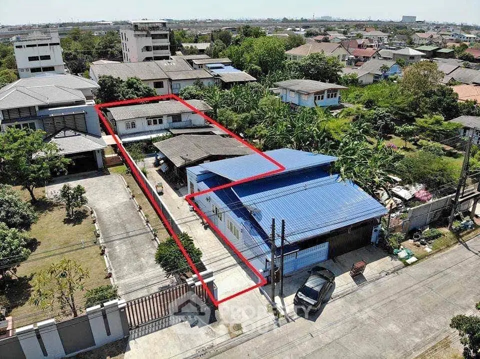 Aerial view of residential property with spacious driveway and surrounding greenery.