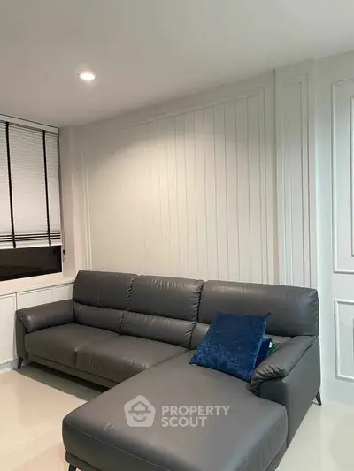Modern living room with sleek gray leather sofa and elegant panel walls