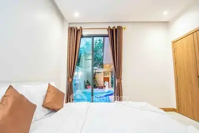 Bright bedroom with pool view through sliding glass doors and elegant curtains.