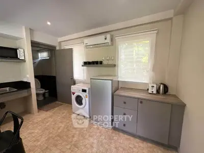 Modern kitchen with washing machine and sleek cabinetry, featuring a compact open layout.