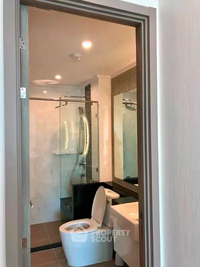 Modern bathroom with glass shower and sleek fixtures in contemporary apartment.