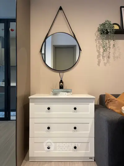 Stylish modern living room with white dresser and round mirror decor.