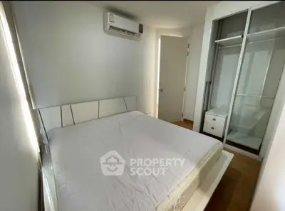 Modern bedroom with sleek design, featuring built-in wardrobe and air conditioning unit.