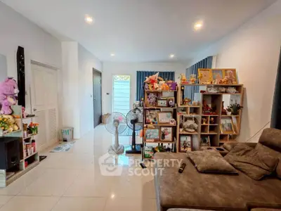 Spacious living room with modern decor and ample natural light, featuring cozy seating and stylish shelving.