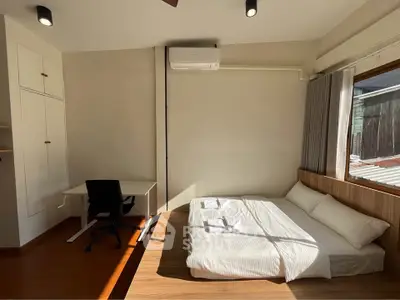 Spacious bedroom with natural light, featuring a cozy bed and a functional study area.