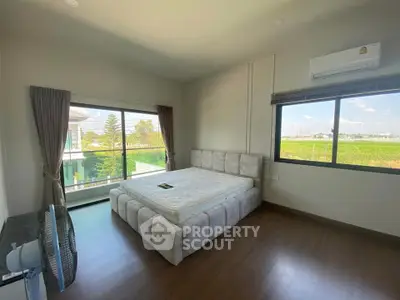 Spacious bedroom with large windows offering scenic views and modern furnishings.