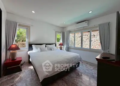 Spacious bedroom with large windows and modern decor in a serene setting.
