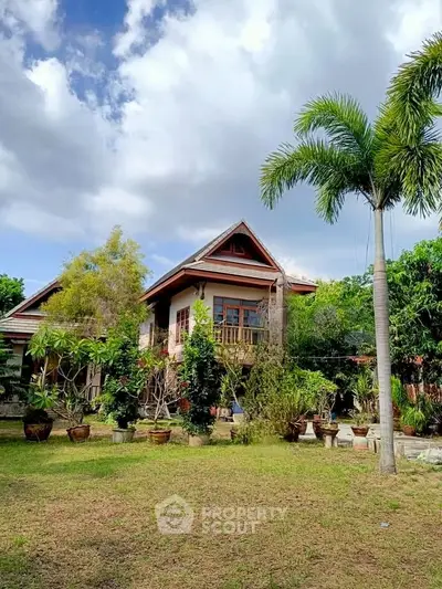 Charming tropical house with lush garden and palm tree, perfect for serene living.