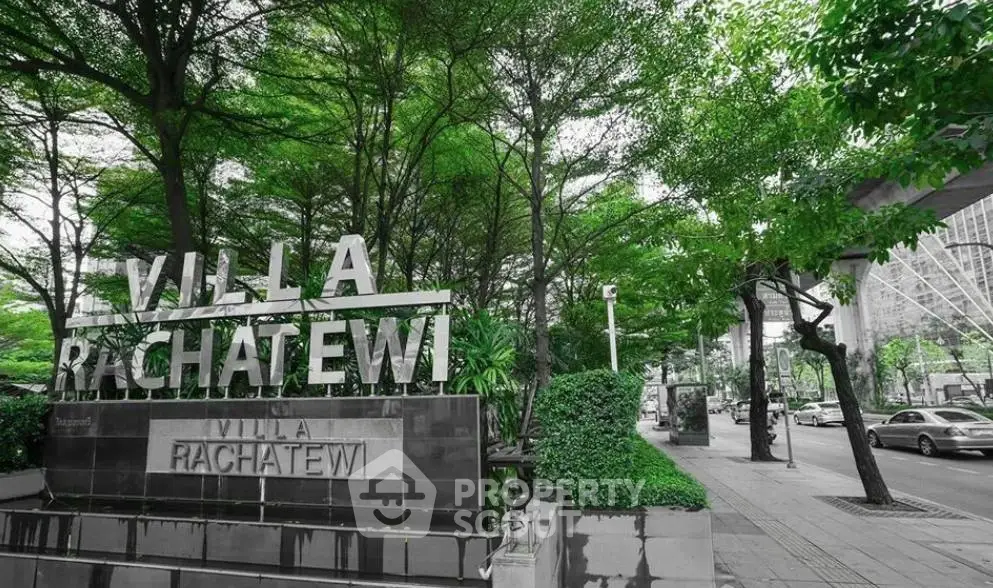 Villa Rachatewi entrance with lush greenery and urban surroundings.