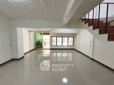 Spacious open-plan living area with glossy tiled floors and staircase, ideal for modern living.
