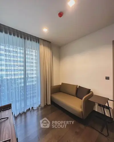 Modern living room with sleek sofa and floor-to-ceiling windows in urban apartment.