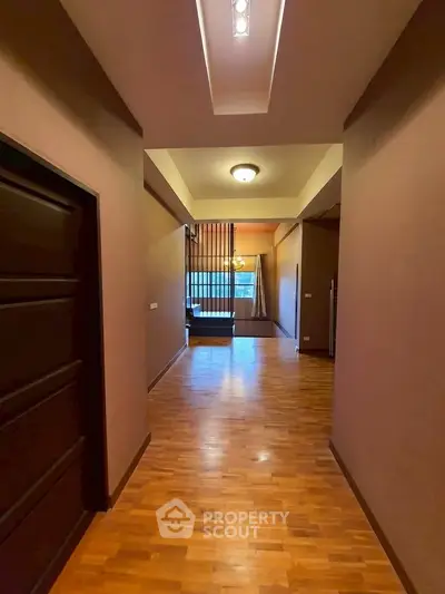 Spacious hallway with wooden flooring leading to a cozy living area.