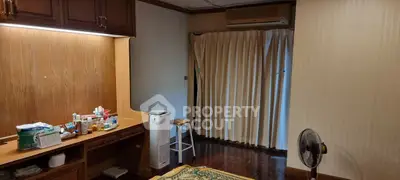 Cozy bedroom with wooden flooring and air conditioning, featuring a study desk and ample natural light.