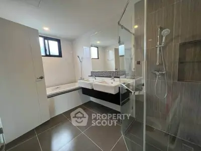 Modern bathroom with dual sinks, glass shower, and bathtub in sleek design.