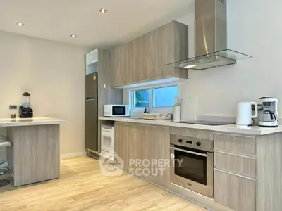Modern kitchen with sleek appliances and wooden cabinetry, featuring an open layout and contemporary design.