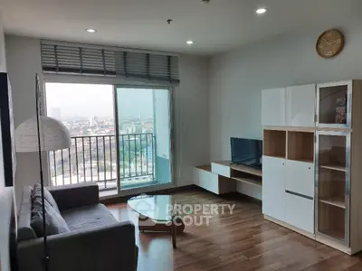 Spacious living room with hardwood floors, modern furniture, and large windows offering a panoramic city view, leading to a cozy balcony.