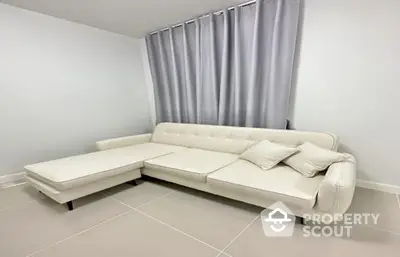 Spacious and modern living room with a large, comfortable white sectional sofa and elegant grey curtains, perfect for relaxation and entertaining guests.