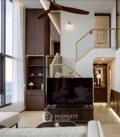 Luxurious modern living room with high ceilings, large windows, and elegant staircase in a stylish apartment.