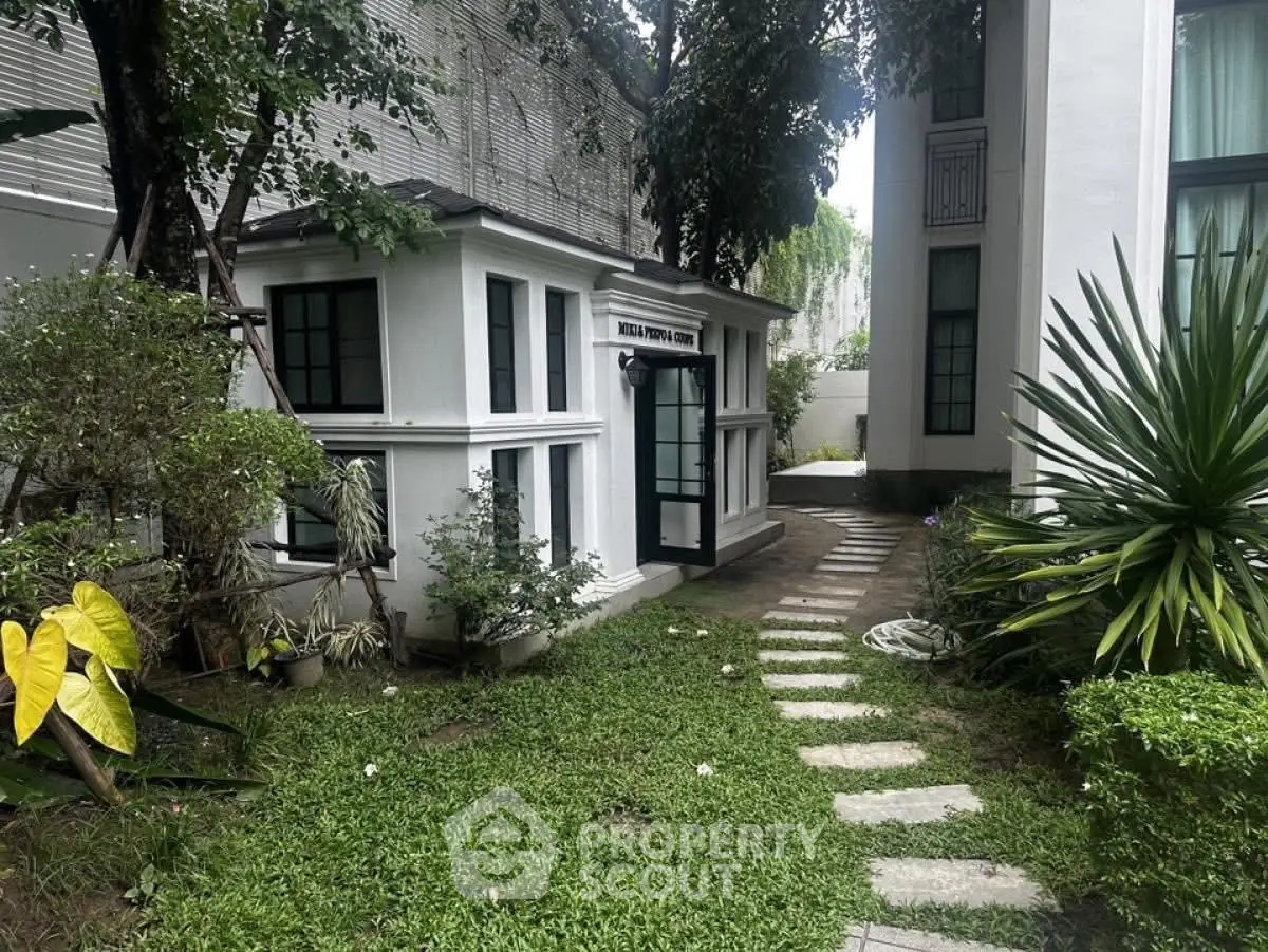 Charming garden entrance with lush greenery and modern architecture.