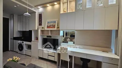 Modern living room with sleek cabinetry and integrated appliances in a stylish apartment.