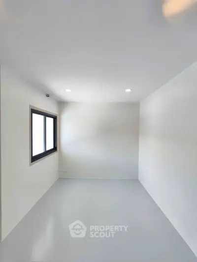 Minimalist empty room with white walls and a window, perfect for customization.