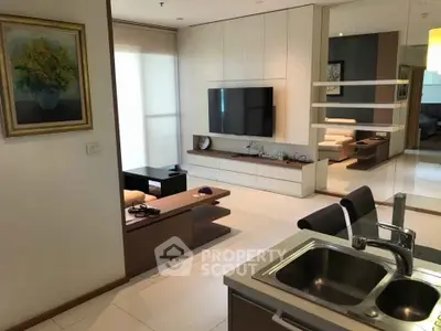 Modern living room with sleek design and integrated kitchen area, featuring a wall-mounted TV and stylish decor.