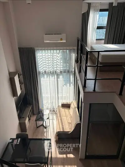 Modern loft apartment with high ceilings and mezzanine bedroom, featuring large windows and stylish furnishings.