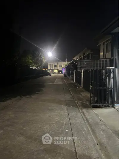 Quiet residential street at night with streetlights illuminating houses.