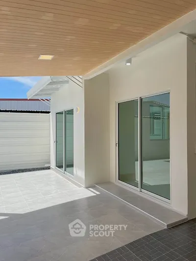 Modern patio with sliding glass doors and covered ceiling, perfect for outdoor relaxation.