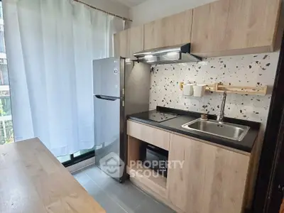 Modern kitchen with sleek cabinetry, stainless steel fridge, and stylish backsplash in a cozy apartment.