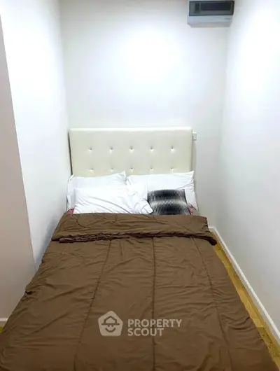 Cozy small bedroom with a double bed and minimalist decor, perfect for compact living spaces.