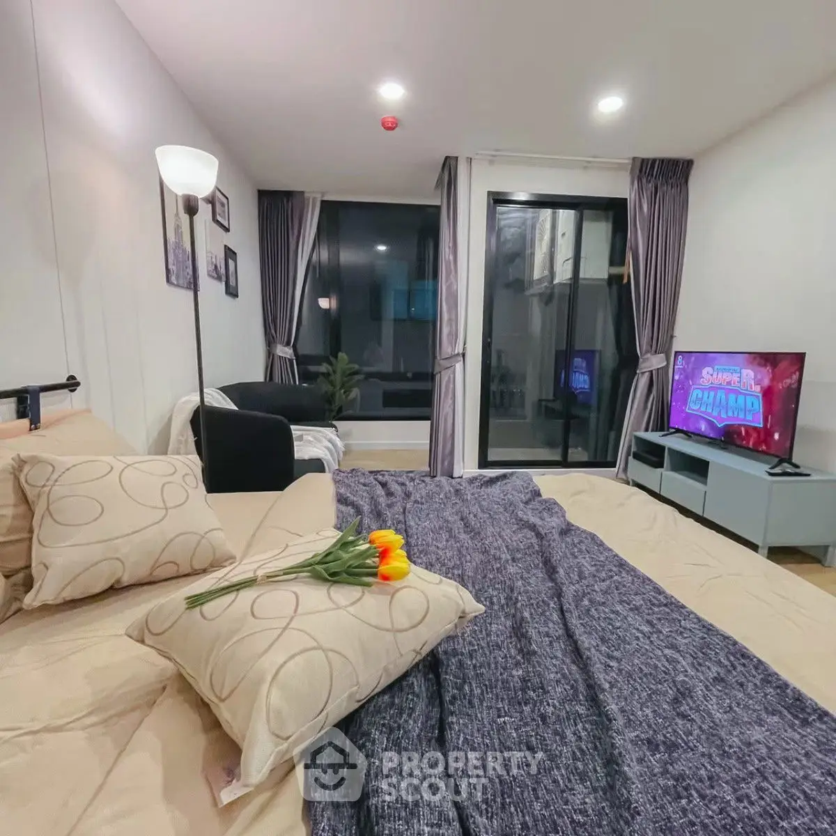 Cozy bedroom with modern decor and balcony access, featuring a stylish TV setup and elegant lighting.