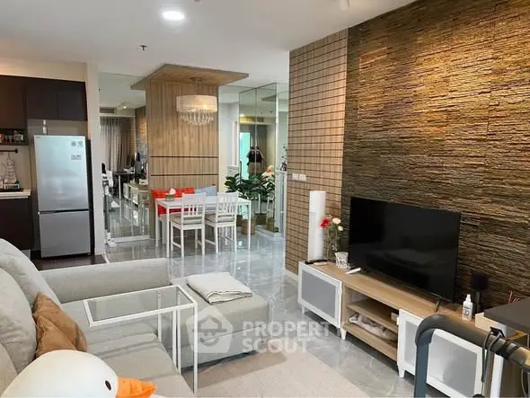 Modern living room with stylish decor and open layout leading to dining area, featuring a cozy sofa and wall-mounted TV.
