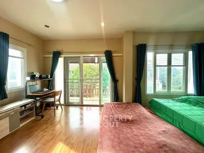 Spacious bedroom with balcony access and natural light, featuring wooden flooring and modern decor.