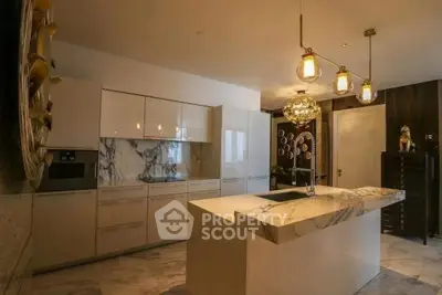 Luxurious modern kitchen with marble countertops and elegant lighting fixtures.