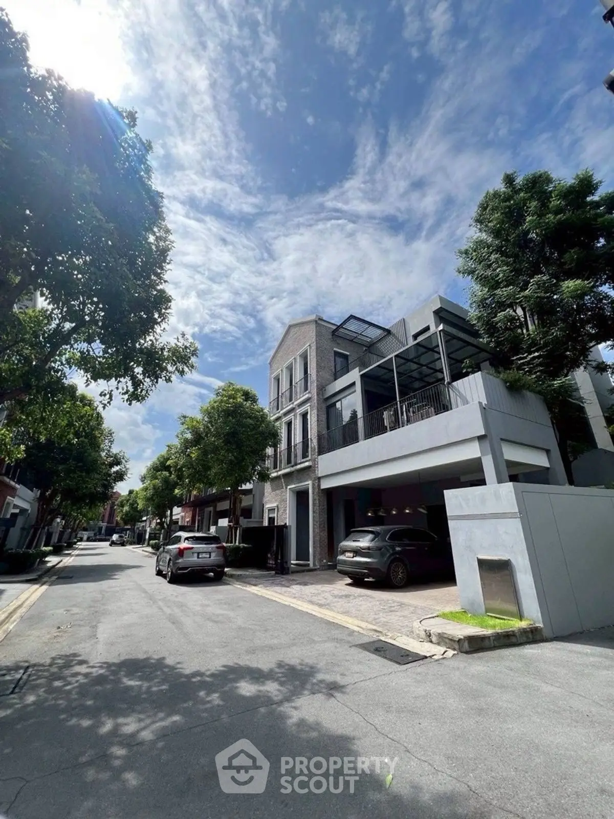 Modern residential building with spacious balcony and street view under clear blue sky.