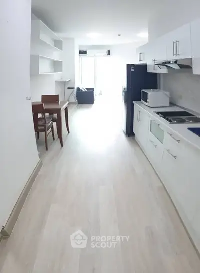 Modern open-layout kitchen and living area with sleek white cabinetry and bright natural light.