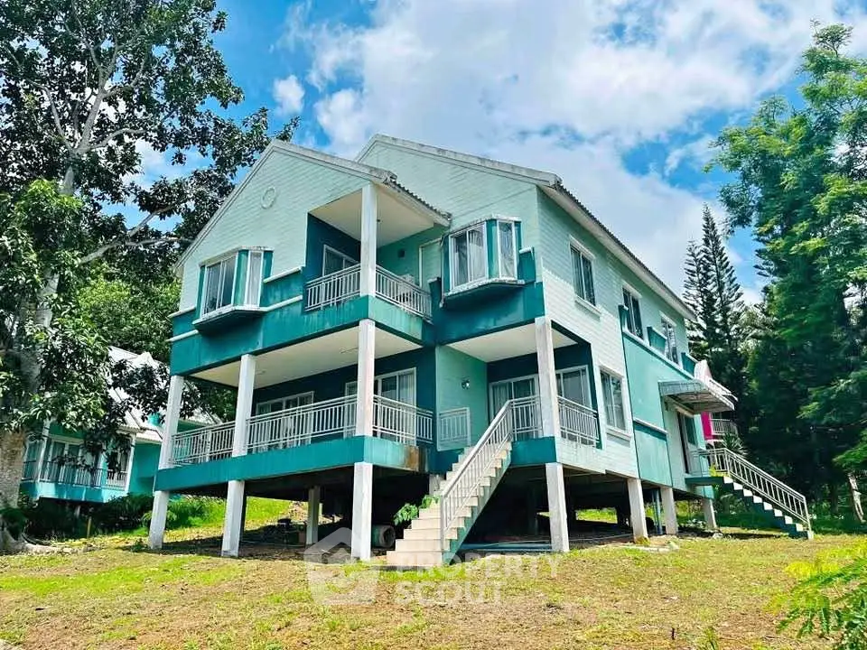 Charming elevated blue house with spacious balconies and lush greenery.