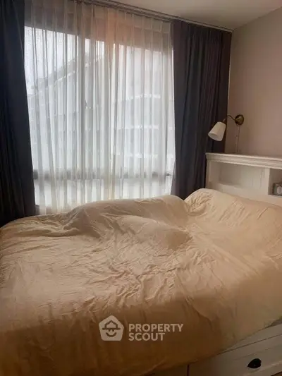 Cozy bedroom with large window and elegant curtains, perfect for relaxation and comfort.