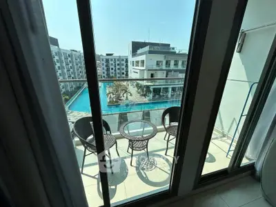 Modern apartment balcony with pool view and stylish outdoor seating.
