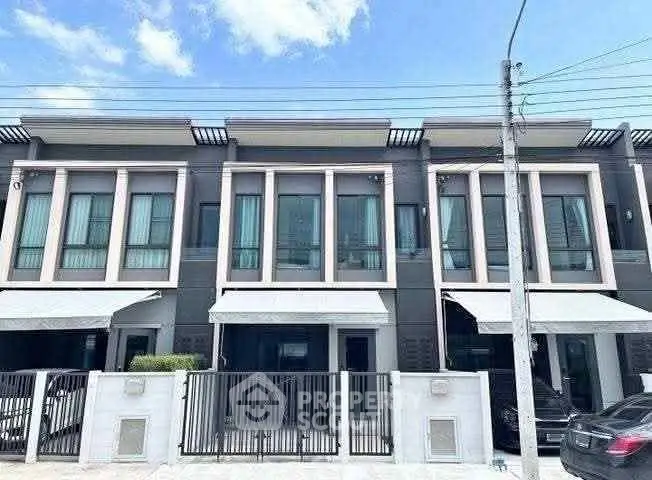 Modern townhouse exterior with sleek design and large windows under a clear blue sky.